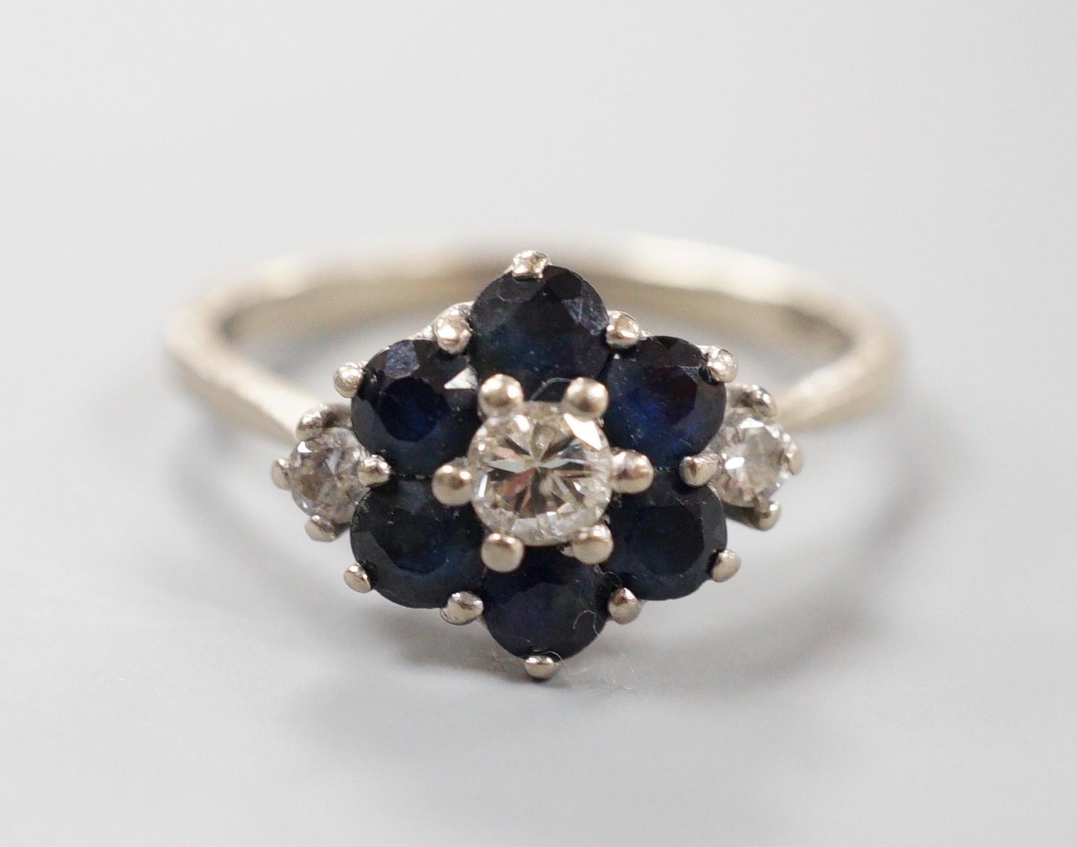 An 18ct white metal, sapphire and diamond set cluster ring, size O, gross weight 4.1 grams.